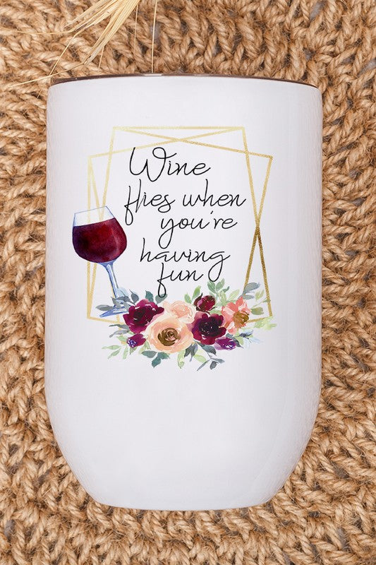 A vibrant 12 oz stainless steel wine tumbler with a fun 'Wine Flies When You're Having Fun' design printed on both sides, complete with a lid and straw.