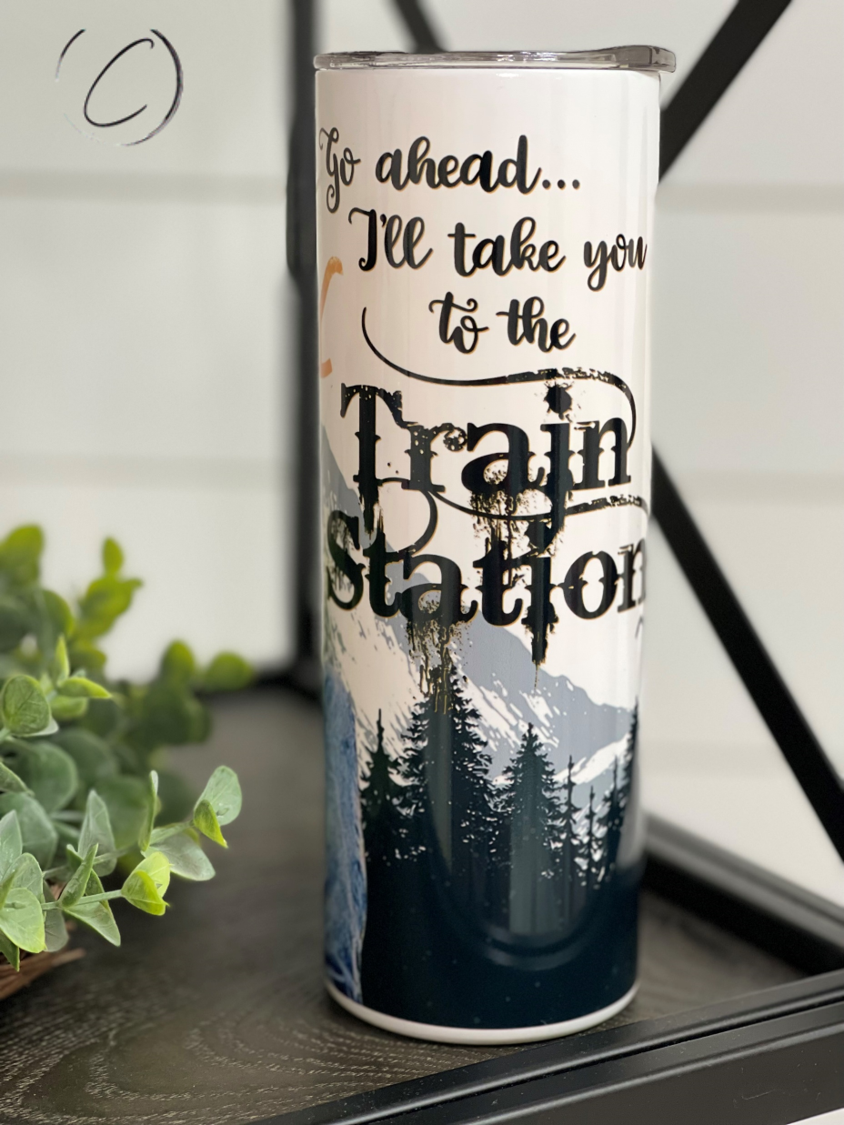 Yellowstone Train Station 20oz UV Orange Skinny Tumbler with a vibrant color-changing effect in sunlight, featuring a reusable straw.