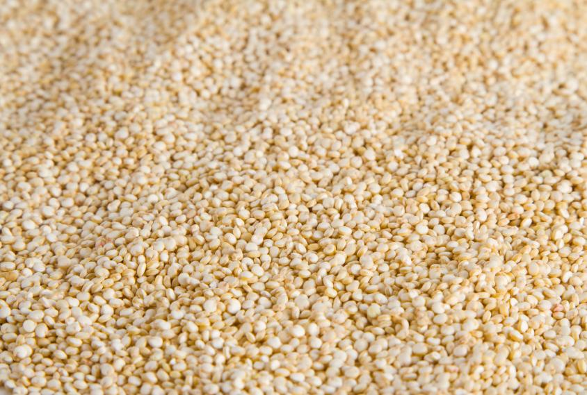 A bowl of 100% organic white quinoa grains, showcasing their fluffy texture and light color, ideal for healthy meals.