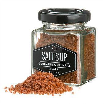 Alaea coarse salt in a glass jar, showcasing its reddish hue and natural texture, perfect for seasoning dishes.