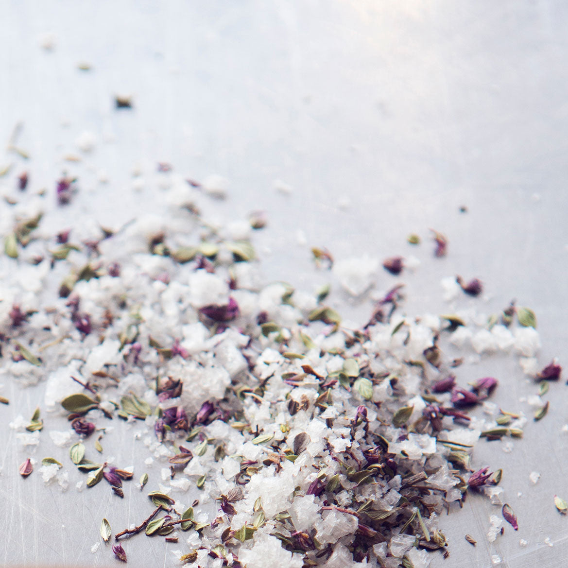 A jar of Arctic Thyme Salt showcasing wild Icelandic thyme and flaky sea salt, set against a rustic wooden background.