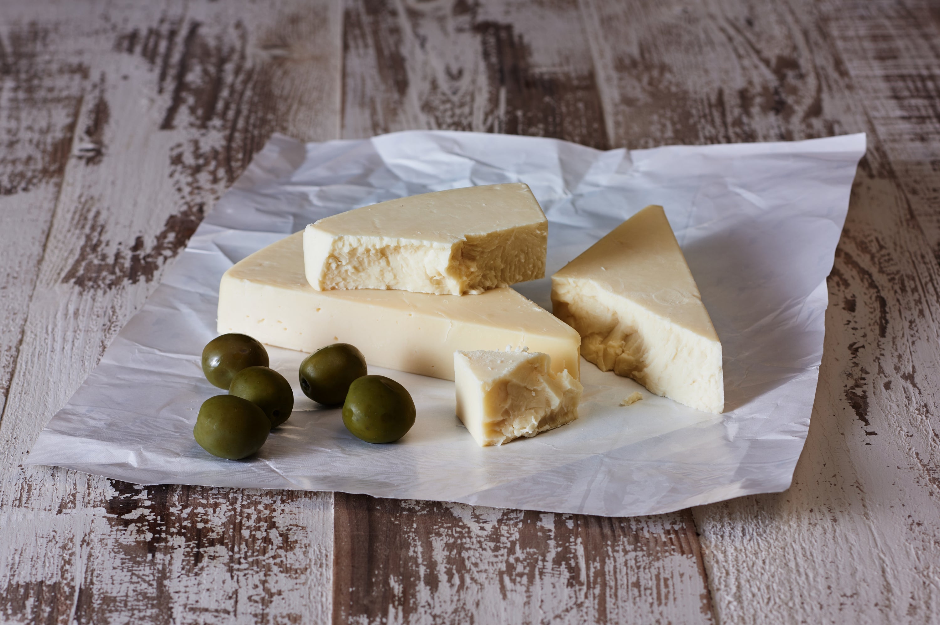 A block of Asiago cheese showcasing its semi-hard texture and rich color, perfect for grating or serving on a cheese platter.