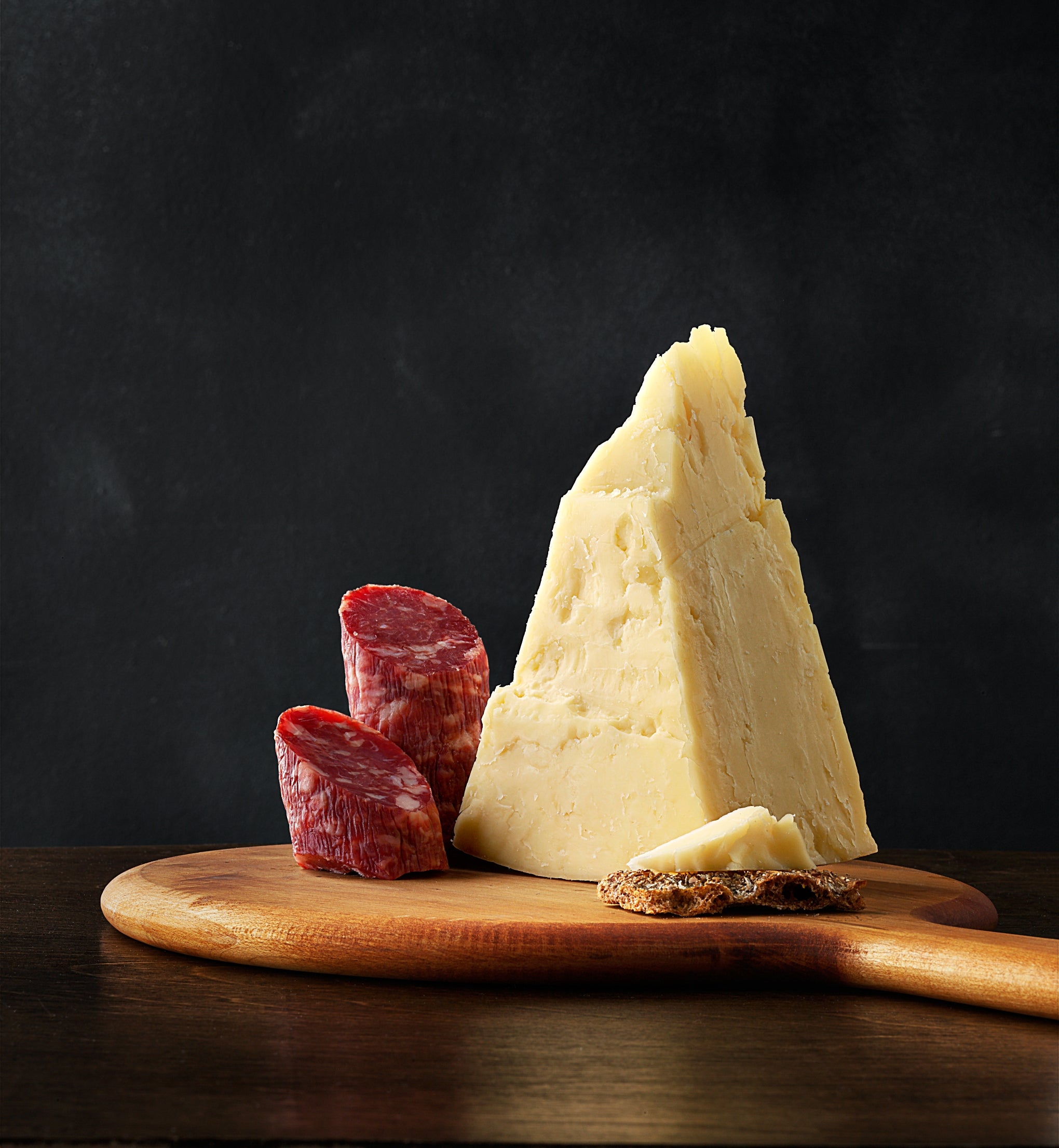 A block of Asiago cheese showcasing its semi-hard texture and rich color, perfect for grating or serving on a cheese platter.