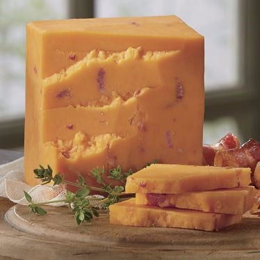 A block of Bacon Cheddar cheese with real bacon bits, showcasing its firm and slightly crumbly texture.