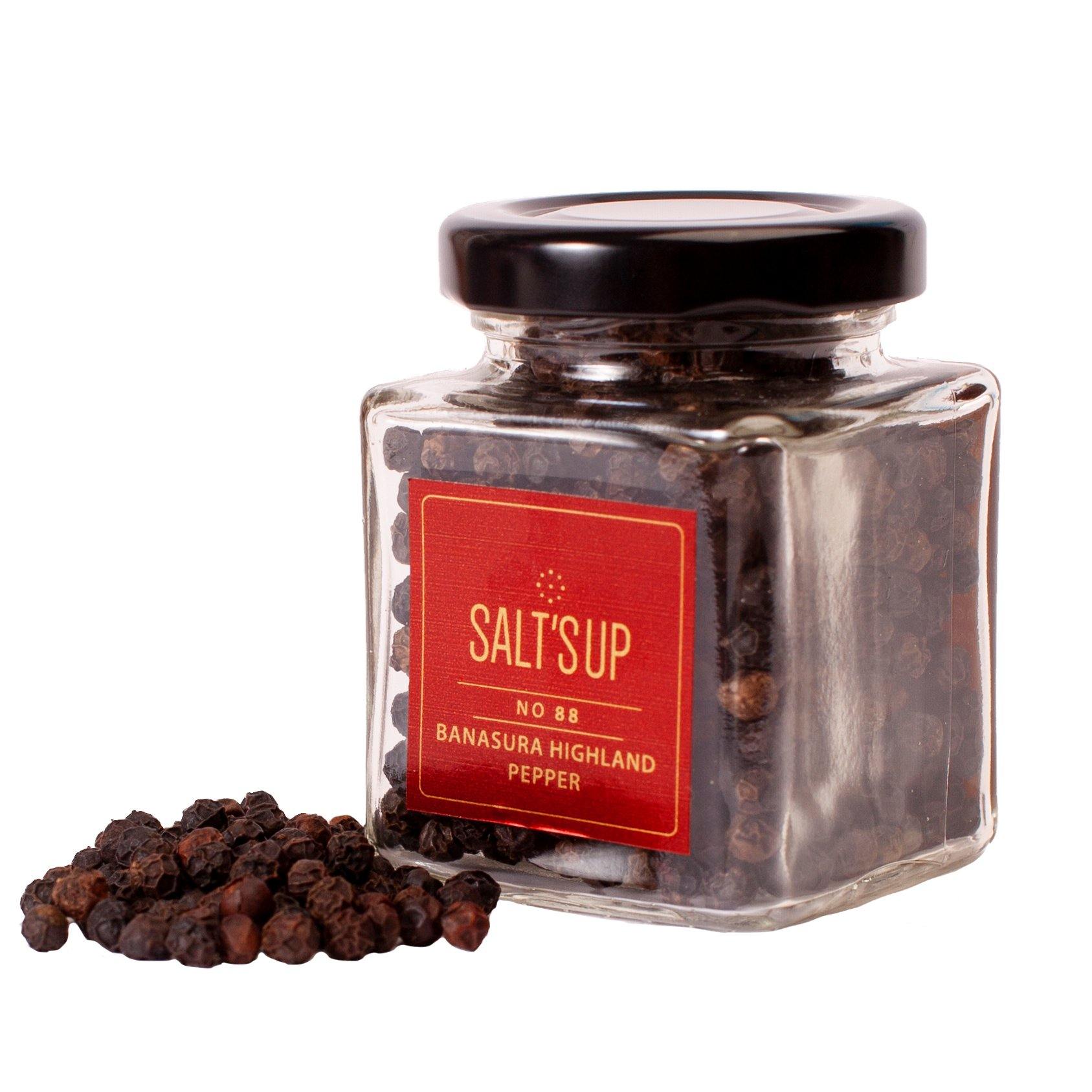 A glass jar containing Banasura Highland pepper, showcasing its rich, dark berries and elegant packaging.