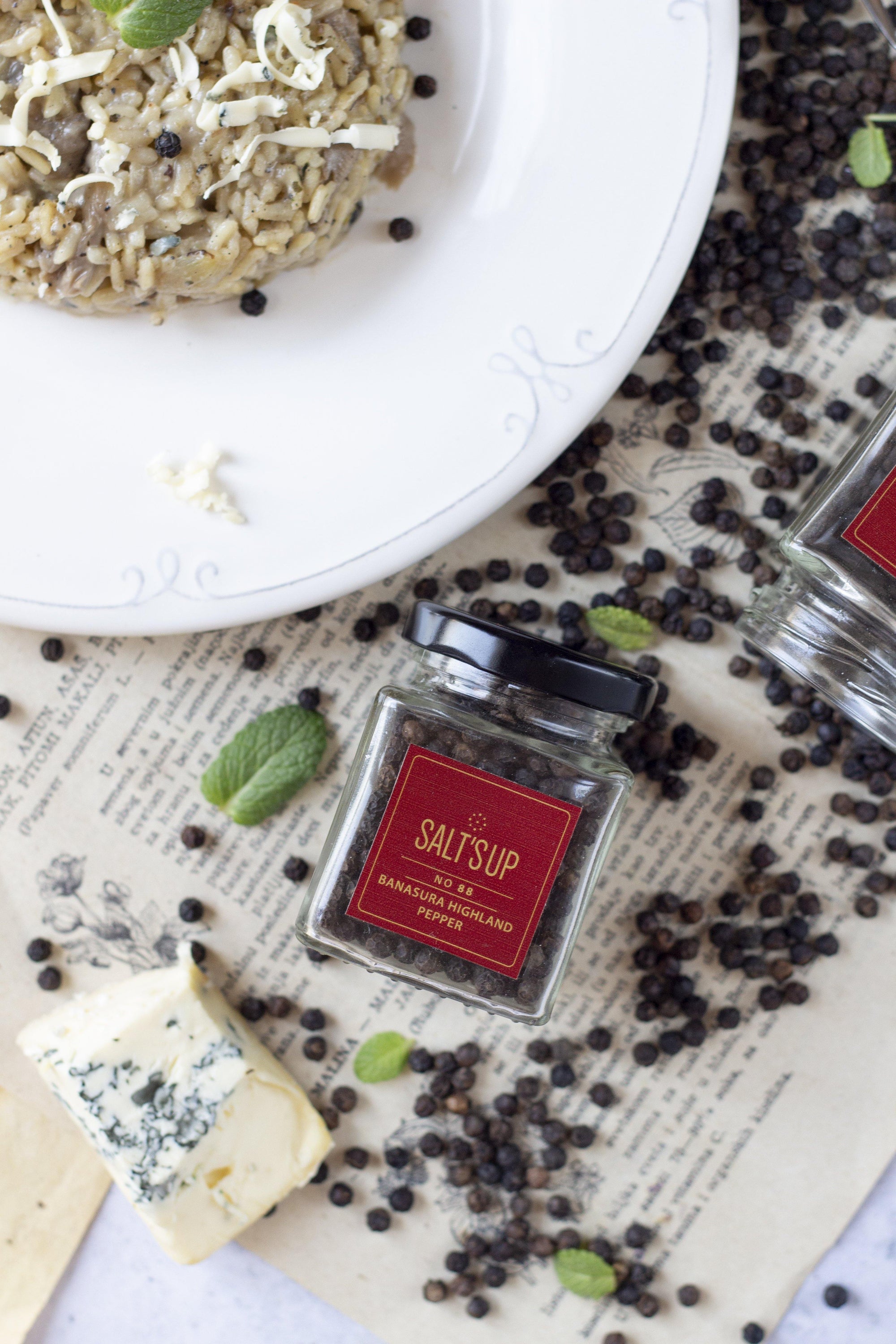 A glass jar containing Banasura Highland pepper, showcasing its rich, dark berries and elegant packaging.