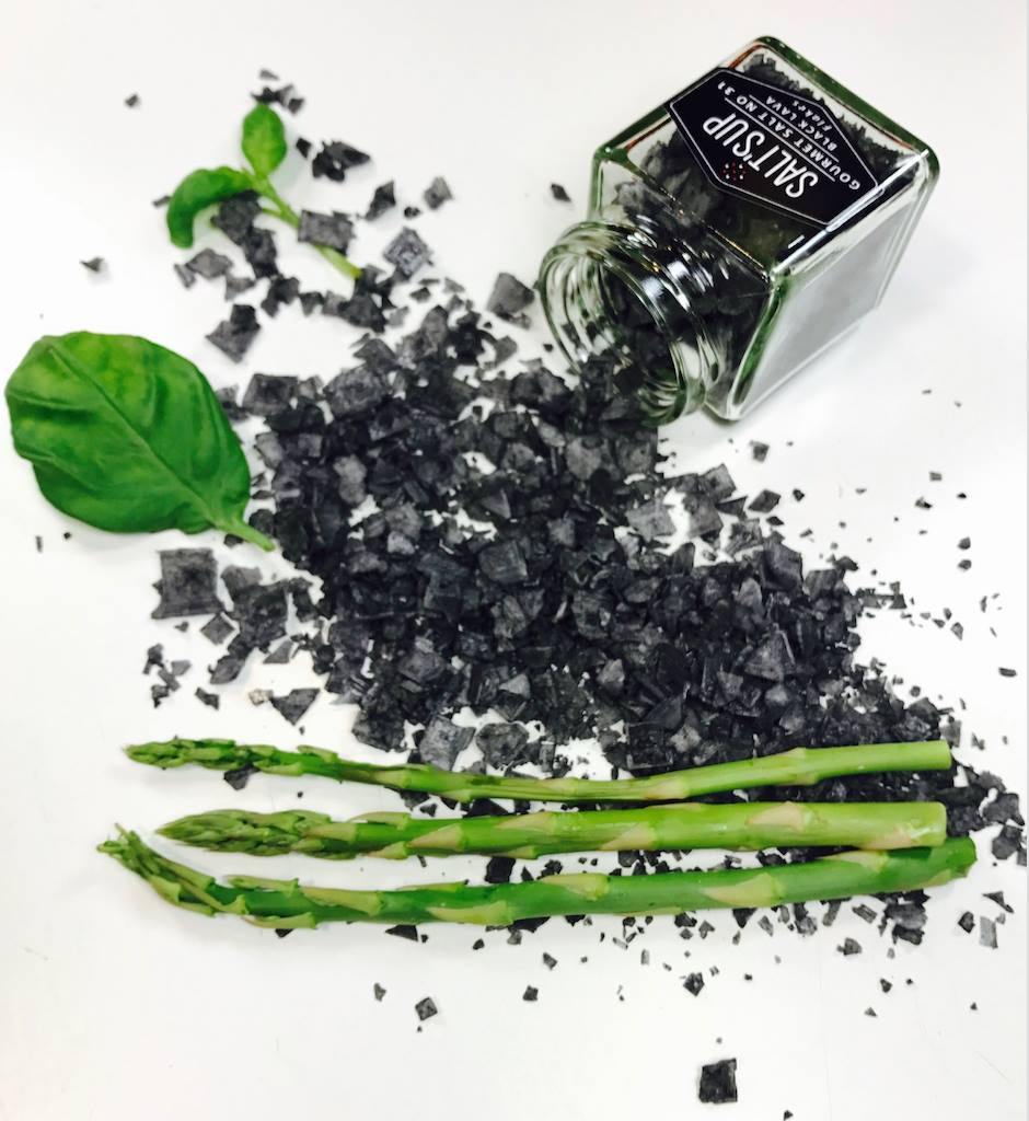 A jar of BLACK LAVA salt flakes showcasing its dramatic black color and flaky texture, ideal for gourmet cooking.