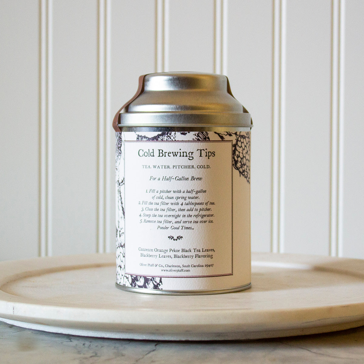 A tin of Blackberry Cold Brew tea with a large wire mesh brewing ball, showcasing the blend of black tea and blackberry leaves.