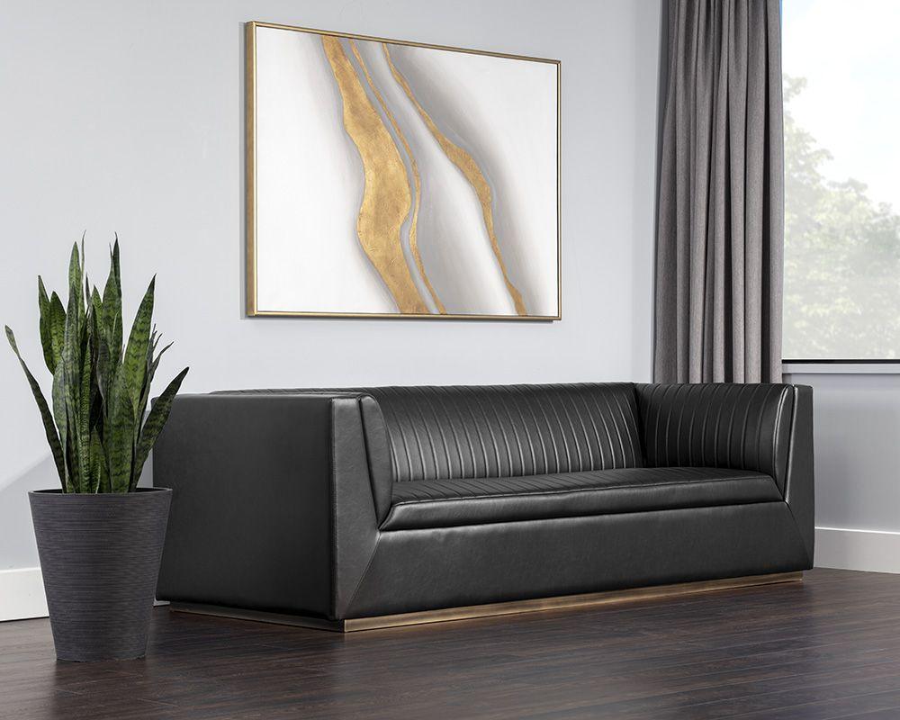 The Bradley Sofa featuring channel tufting in vintage blue faux leather with rustic bronze steel legs.