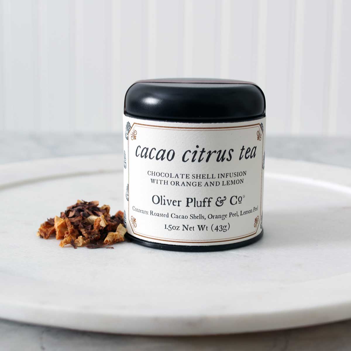 A tin of Martha Washington's Cacao Citrus Tea containing loose roasted cacao shells and dried citrus peels, showcasing a rich blend of flavors.