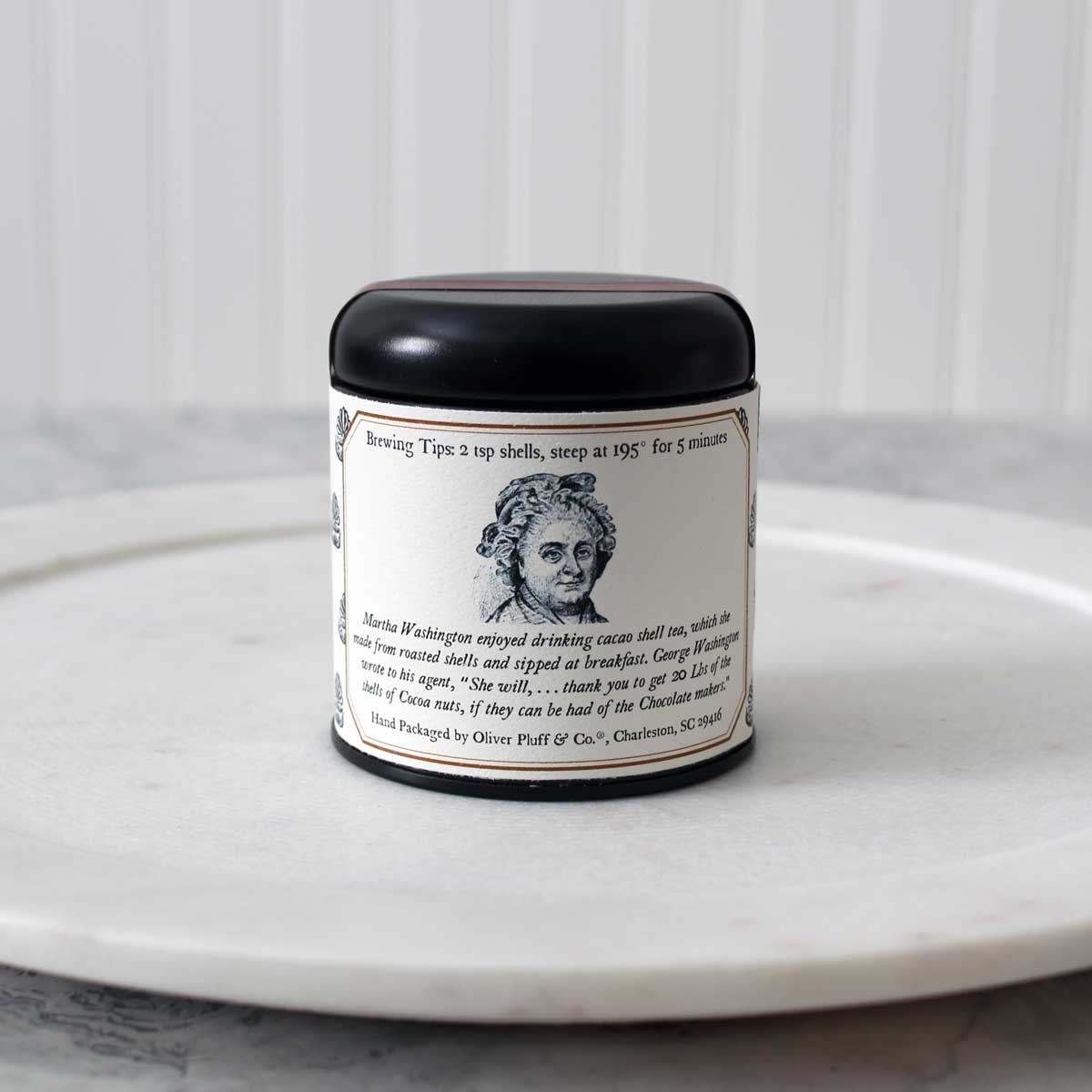 A tin of Martha Washington's Cacao Citrus Tea containing loose roasted cacao shells and dried citrus peels, showcasing a rich blend of flavors.