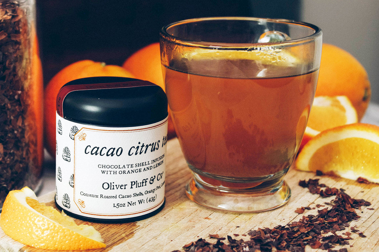 A tin of Martha Washington's Cacao Citrus Tea containing loose roasted cacao shells and dried citrus peels, showcasing a rich blend of flavors.