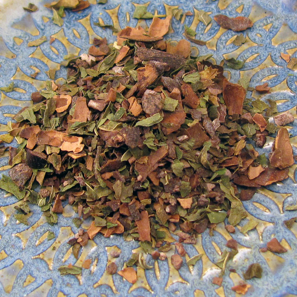 A tin of Martha Washington's Cacao Mint Tea containing loose roasted cacao shells blended with peppermint leaves, set against a rustic background.