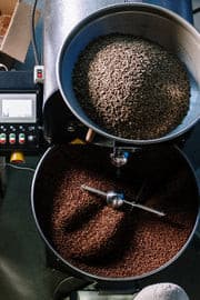 A steaming cup of Café Blend Coffee on a wooden table, surrounded by coffee beans and a cozy cafe setting.