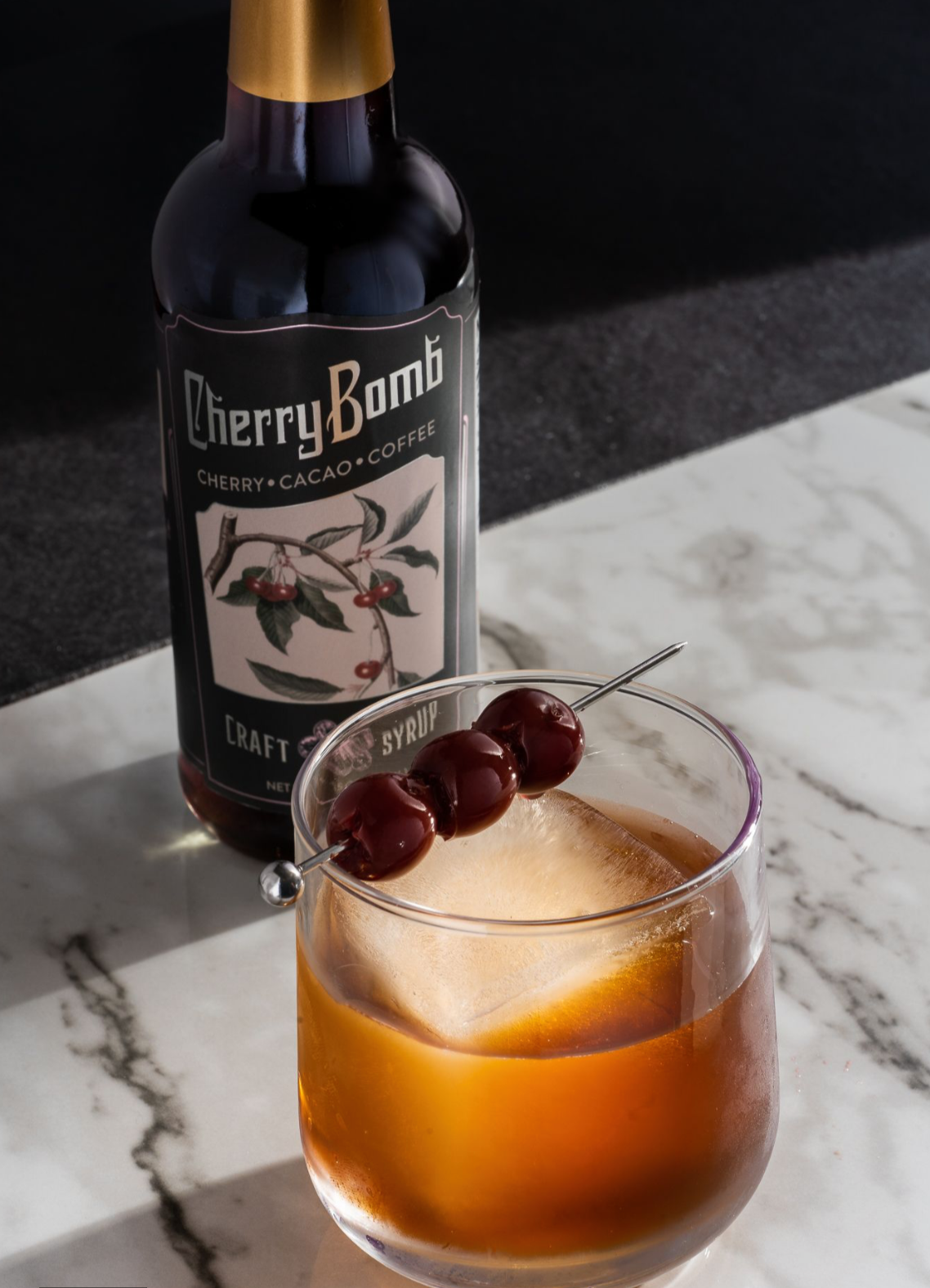 A bottle of Cherry Bomb Syrup featuring a rich blend of cherry, coffee, and cacao, with a vibrant label showcasing its all-natural ingredients.