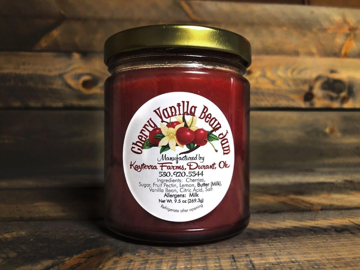 A jar of Cherry Vanilla Bean Jam showcasing vibrant red cherries and a hint of vanilla bean, perfect for spreading on biscuits or ice cream.