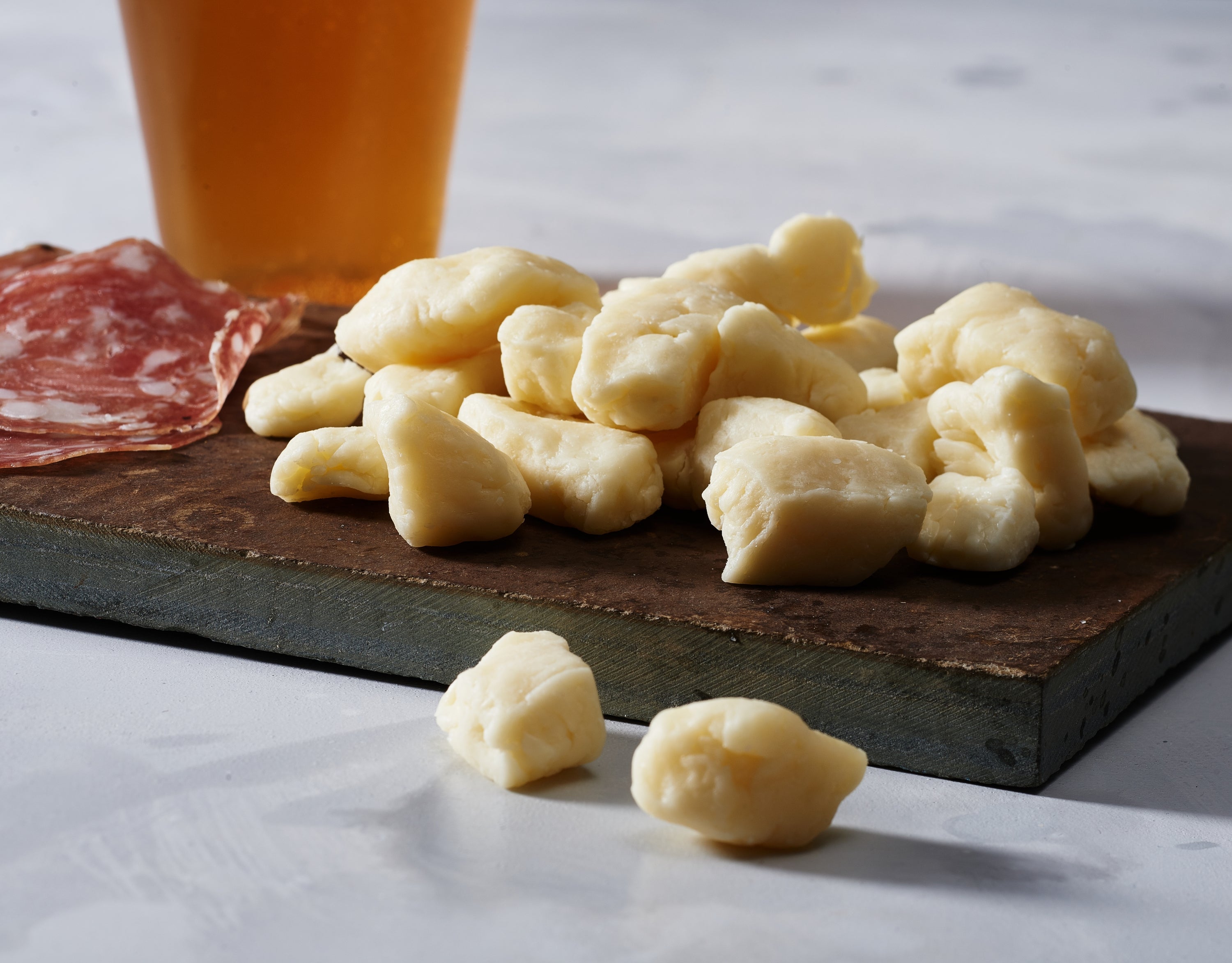 A close-up of fresh white cheese curds, showcasing their irregular shapes and creamy texture, perfect for snacking or cooking.