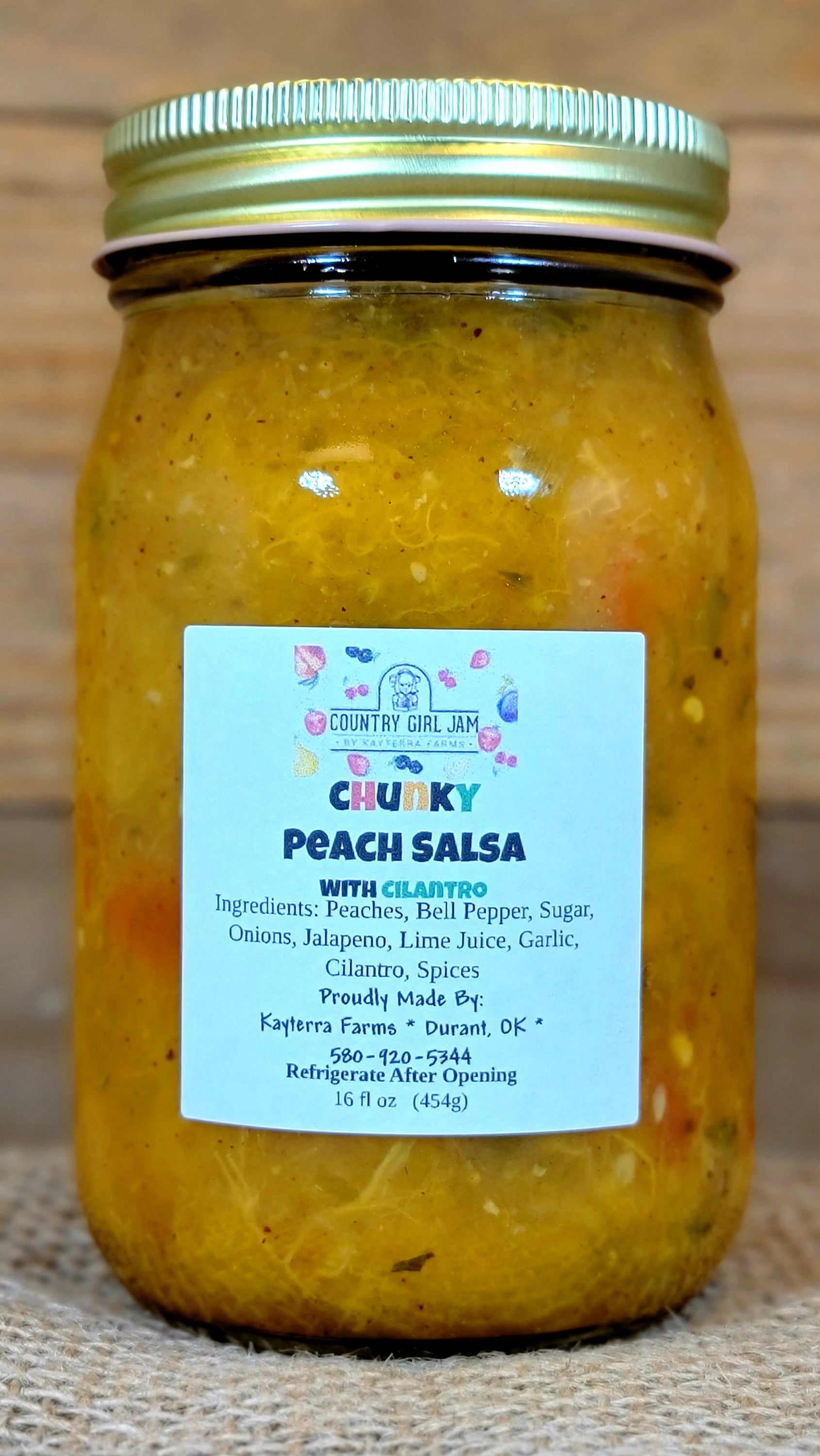 A jar of Chunky Peach Salsa with fresh peaches and chips, showcasing its vibrant color and chunky texture.