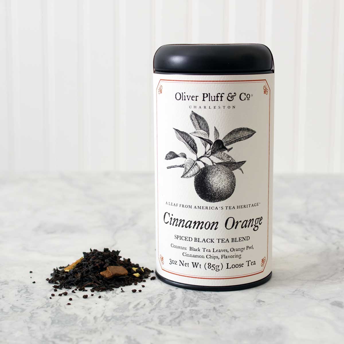 Cinnamon Orange Spice Loose Tea in a matte black signature tin, showcasing the blend of black tea, orange peel, and cinnamon chips.