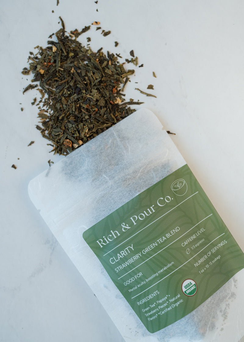 A vibrant package of Clarity Strawberry Green Tea Blend featuring strawberries and papaya, showcasing its organic ingredients.