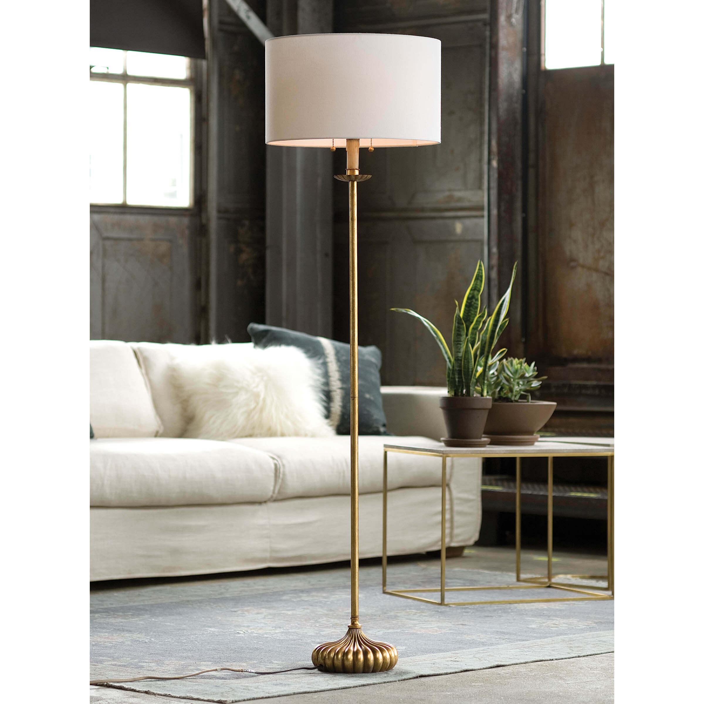 Clove Stem Floor Lamp with antiqued gold base and white linen shade, standing elegantly in a stylish room.