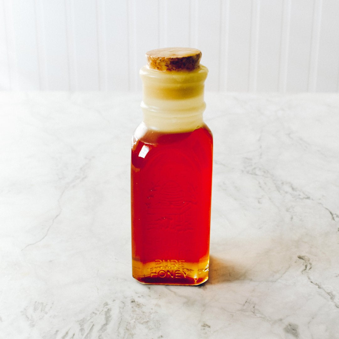 Colonial Honey Jar filled with pure wildflower honey, featuring a cork seal and beeswax dip, showcasing its vintage Muth design.