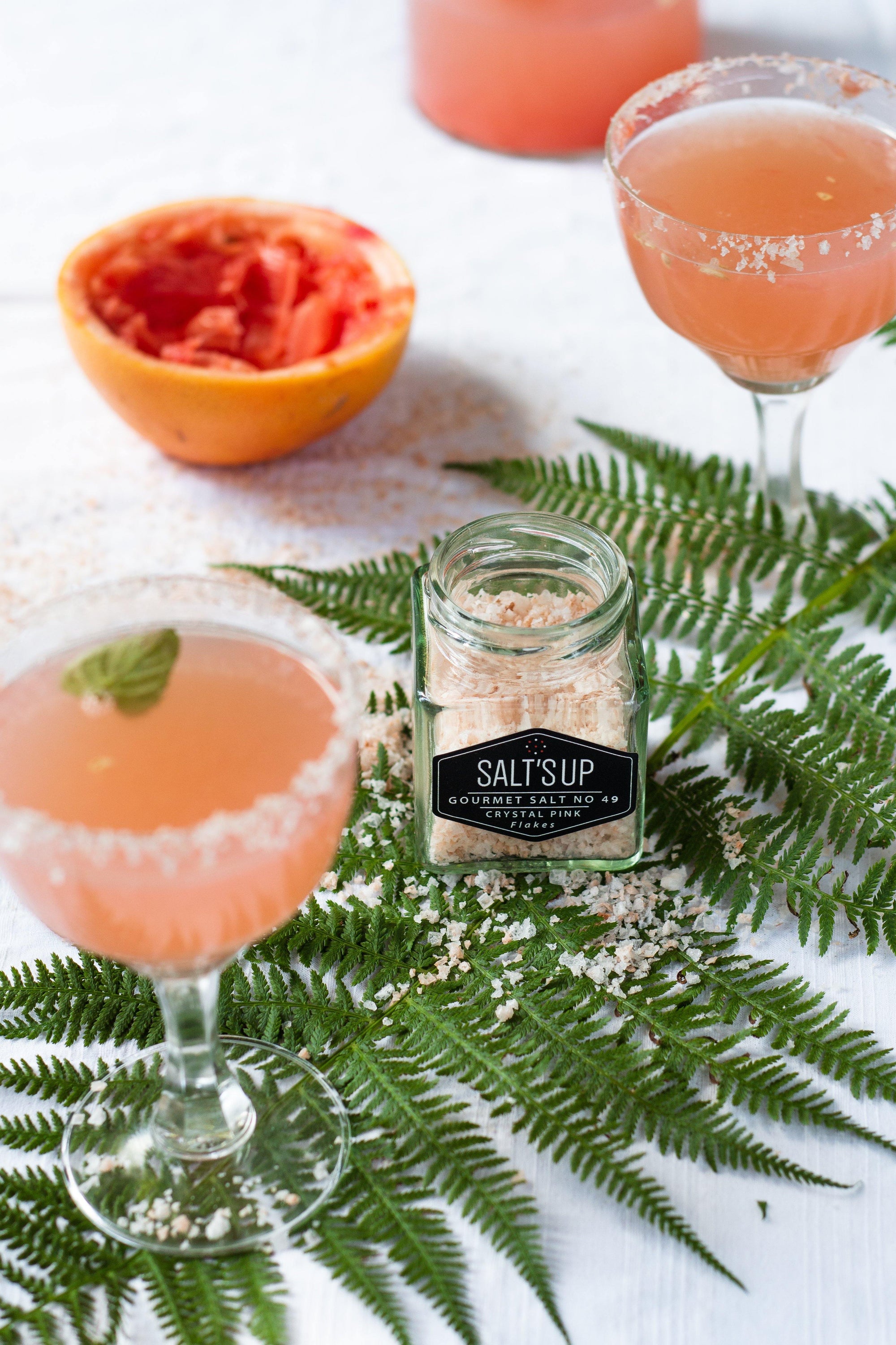 A glass jar filled with CRYSTAL PINK salt flakes, showcasing their beautiful pink color and flaky texture.