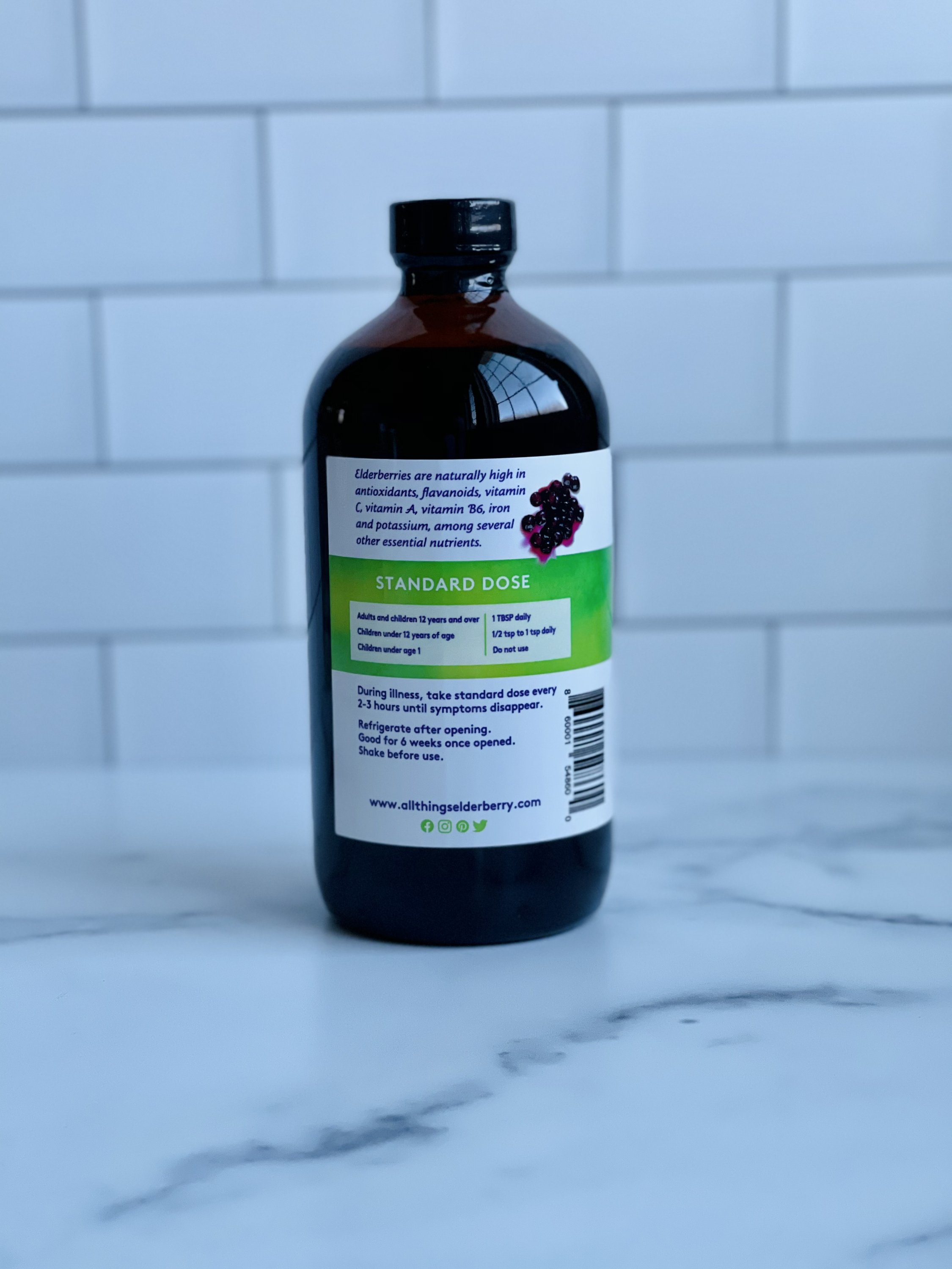 A bottle of Elderberry Elixir made with fresh elderberries, showcasing its rich purple color and organic ingredients.