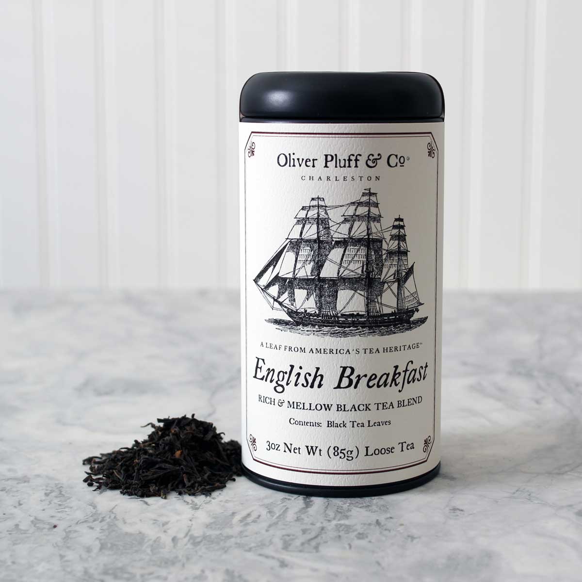 A matte black signature tea tin filled with English Breakfast Loose Tea, showcasing its elegant design and rich contents.