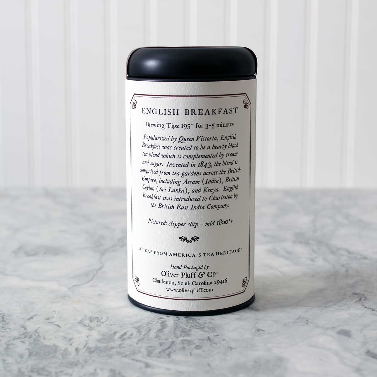 A matte black signature tea tin filled with English Breakfast Loose Tea, showcasing its elegant design and rich contents.