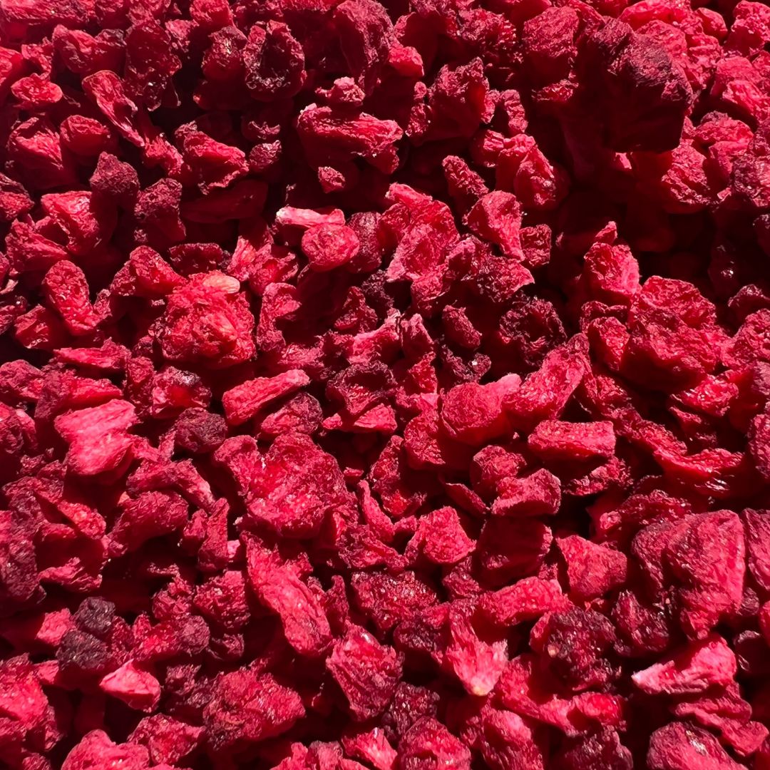 A bowl of vibrant freeze dried raspberry grits, showcasing their rich color and texture, perfect for culinary use.