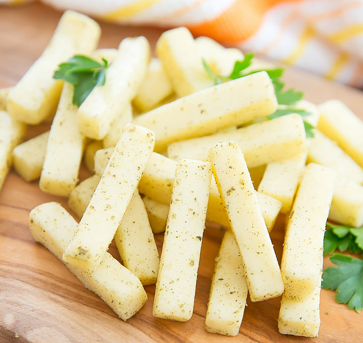 A block of Garlic & Herb Jack cheese with herbs and garlic, showcasing its creamy texture and rich flavor.