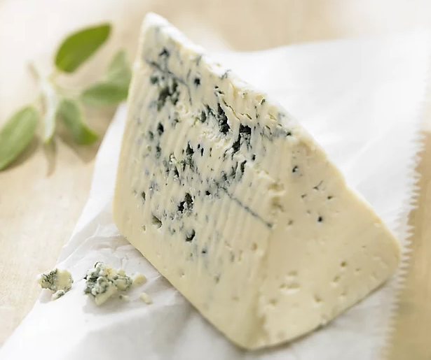 A wedge of Gorgonzola cheese showcasing its firm, crumbly texture and greenish-blue mold veins, served on a wooden board.