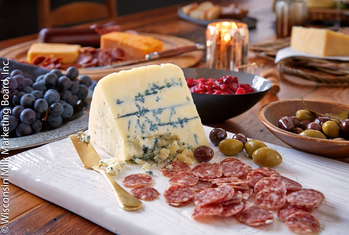 A wedge of Gorgonzola cheese showcasing its firm, crumbly texture and greenish-blue mold veins, served on a wooden board.