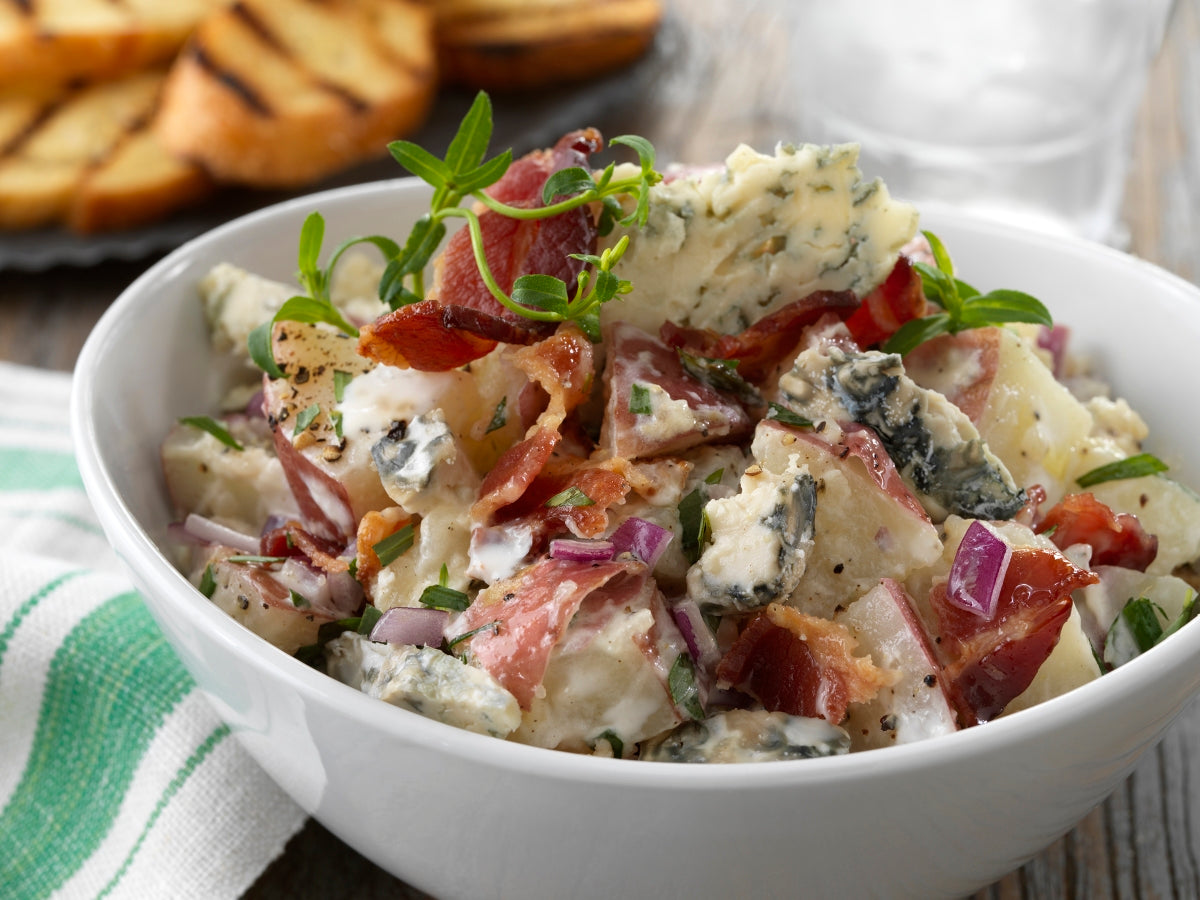 A wedge of Gorgonzola cheese showcasing its firm, crumbly texture and greenish-blue mold veins, served on a wooden board.