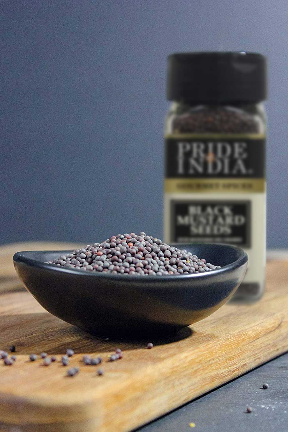 A close-up of Gourmet Black Mustard Seed Whole, showcasing round black-brown seeds in a rustic wooden bowl, emphasizing their rich texture and quality.