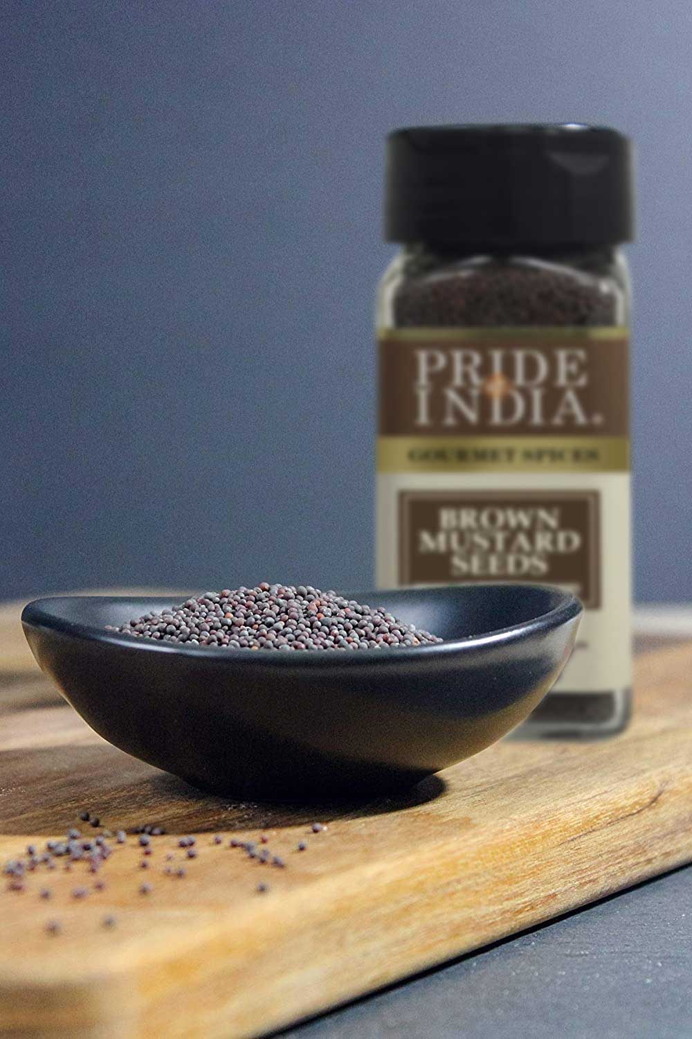 A close-up of whole brown mustard seeds in a wooden bowl, showcasing their round shape and dark brown color, ideal for culinary use.