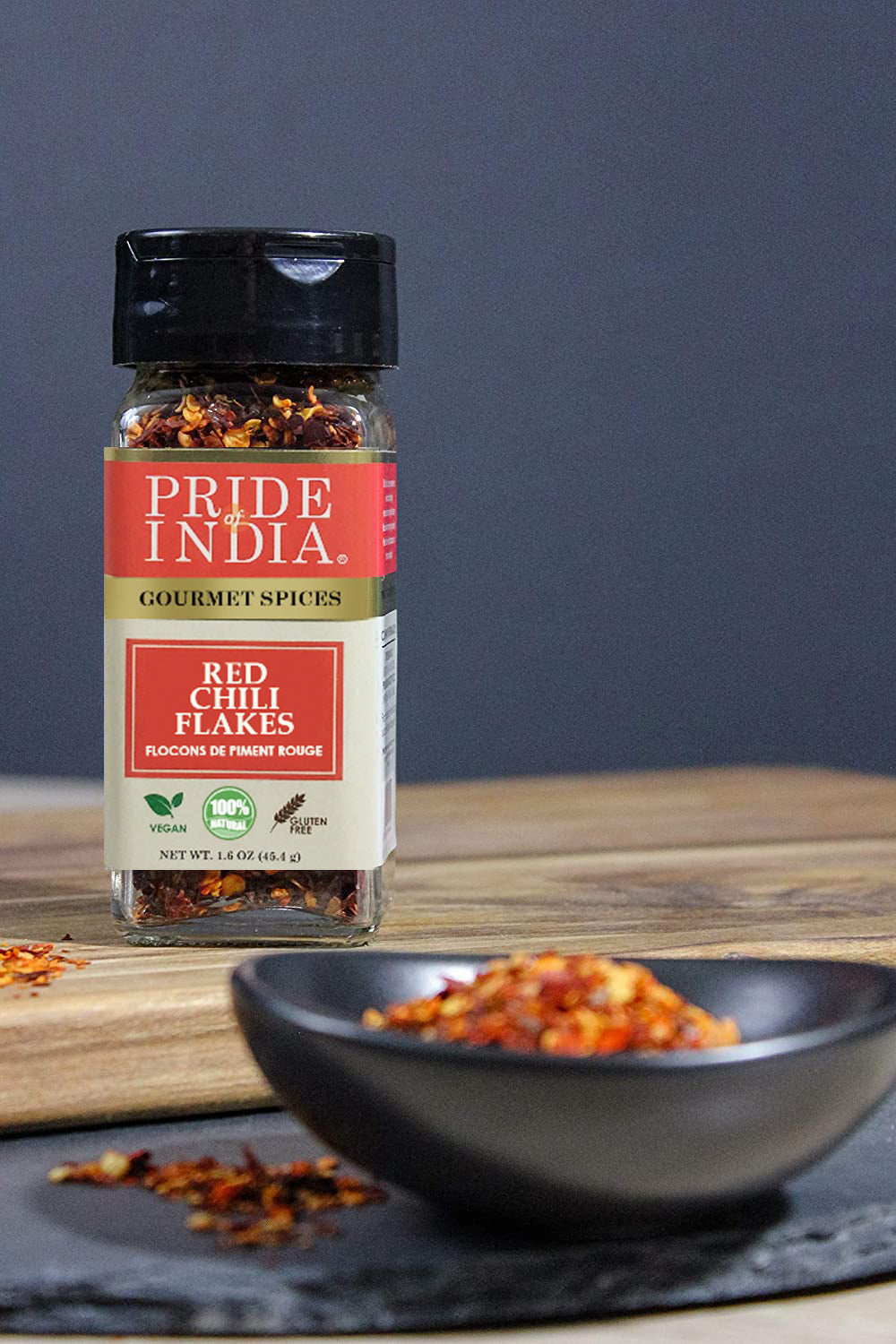 A jar of Pride Of India Gourmet Red Chili Flakes Hot, showcasing vibrant red crushed chili peppers, ideal for adding spice to dishes.