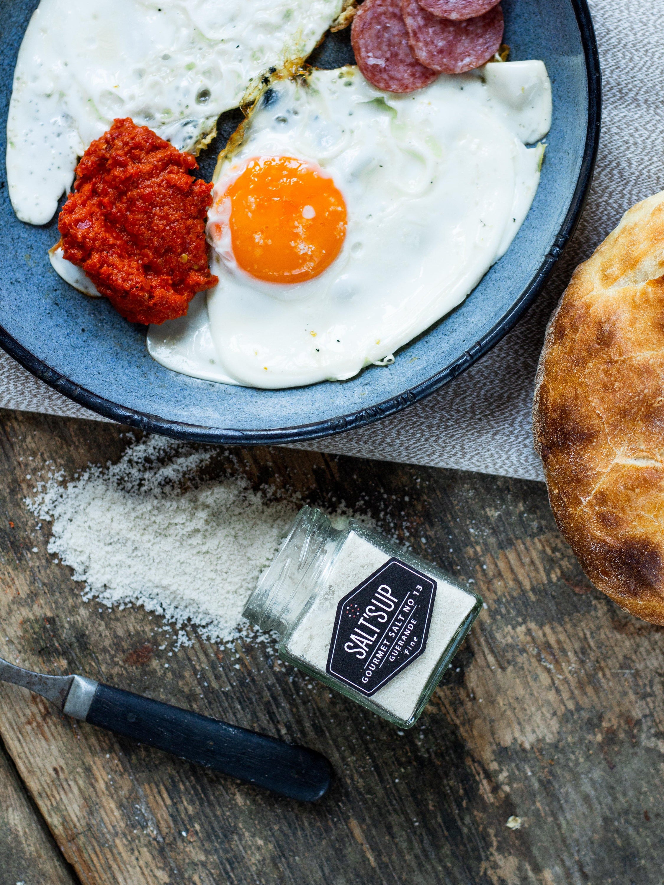 A jar of GUERANDE fine salt showcasing its grey color and artisanal packaging, ideal for enhancing flavors in cooking.