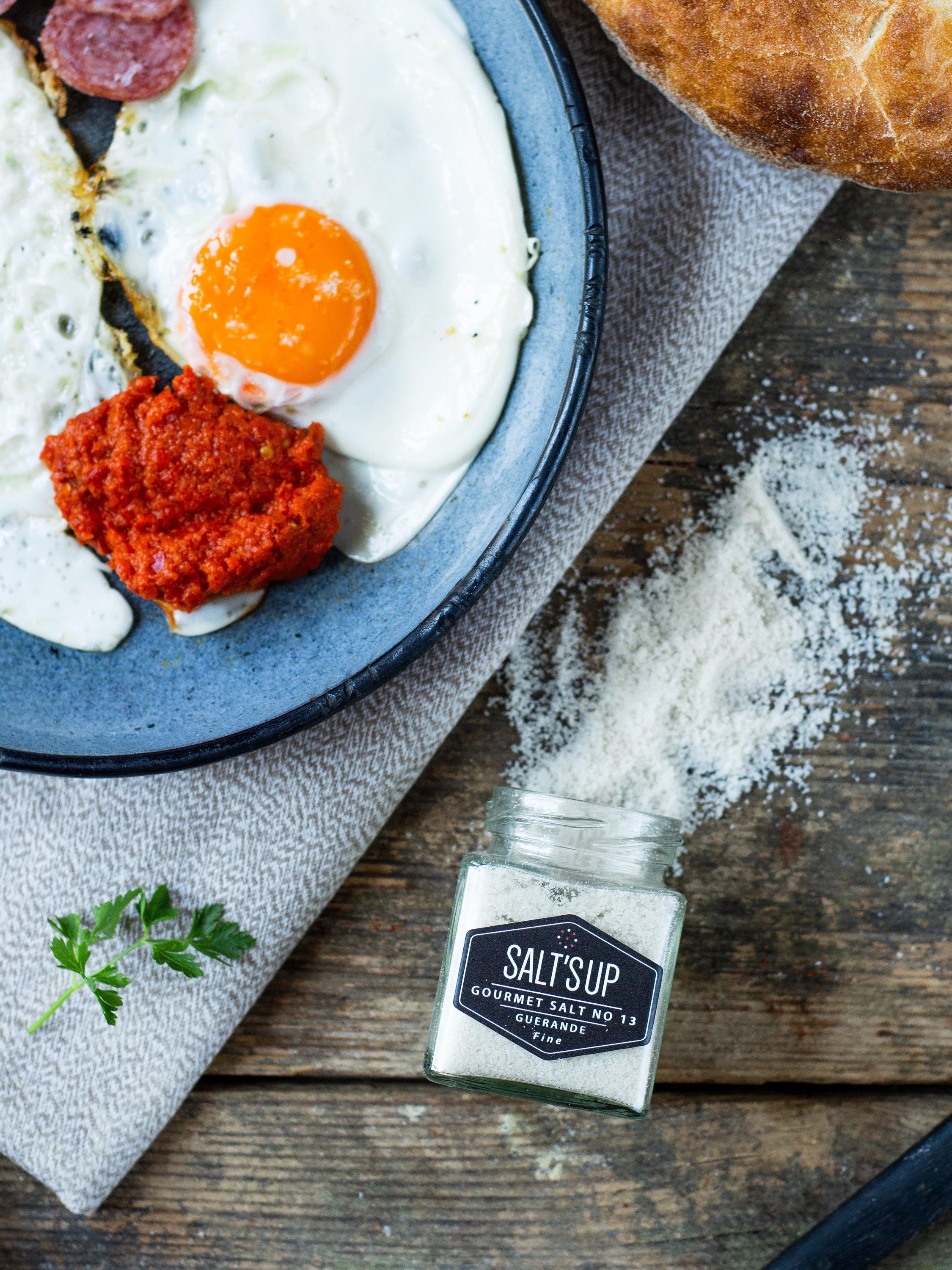 A jar of GUERANDE fine salt showcasing its grey color and artisanal packaging, ideal for enhancing flavors in cooking.