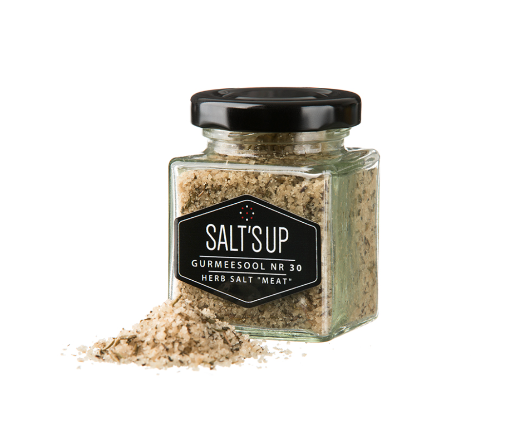 A glass jar of HERB SALT 'MEAT' coarse featuring Flor de Sal and aromatic herbs, ideal for seasoning meat dishes.