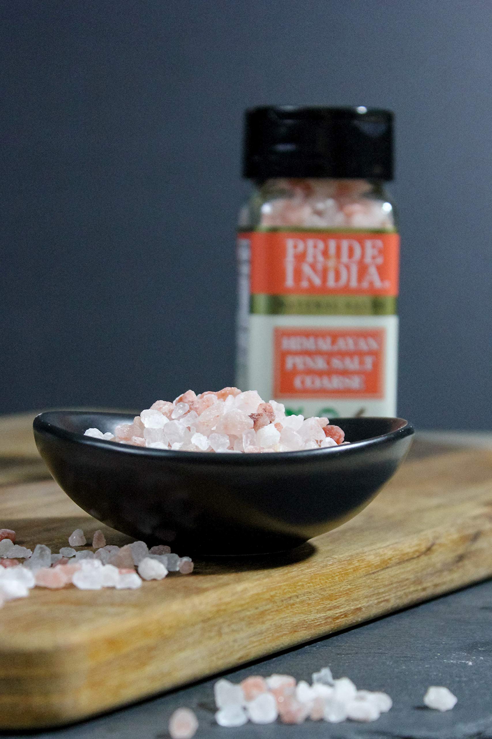 Coarse grind Himalayan pink rock salt in a wooden bowl, showcasing its natural reddish-pink color and texture.