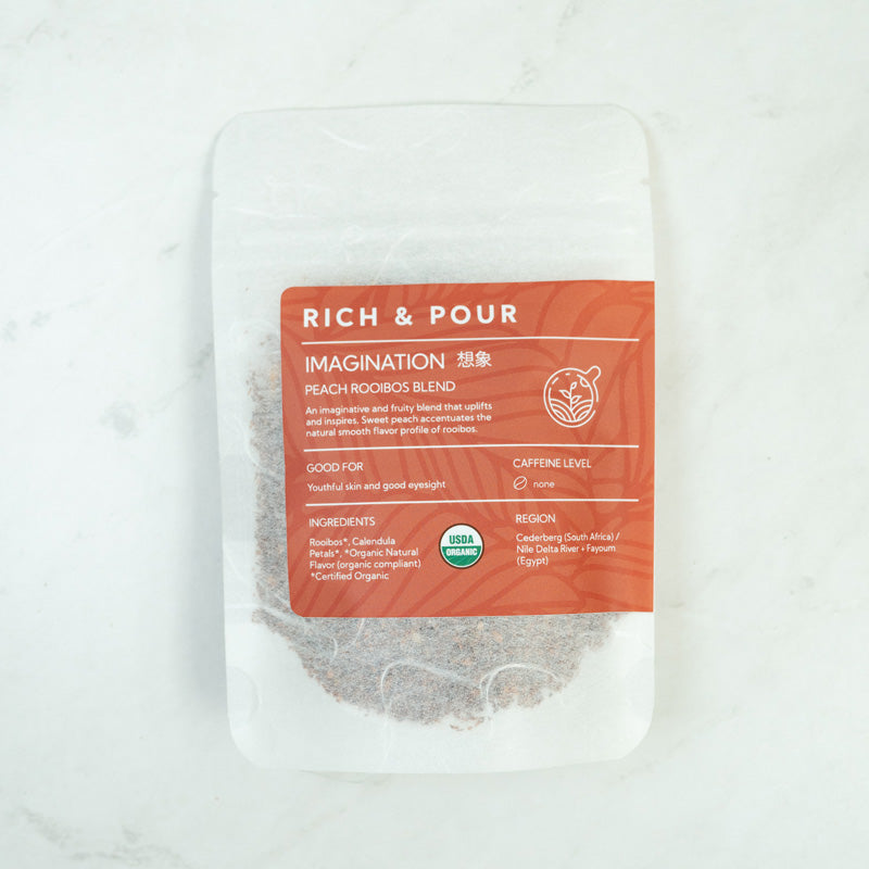 A vibrant package of Imagination Peach Rooibos Blend tea, showcasing its organic ingredients and fruity flavor profile.