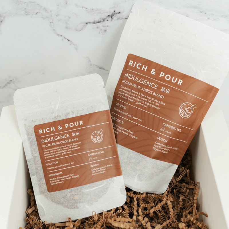 A cup of Pecan Pie Rooibos Blend tea with loose leaf ingredients and biodegradable packaging, showcasing its rich color and texture.