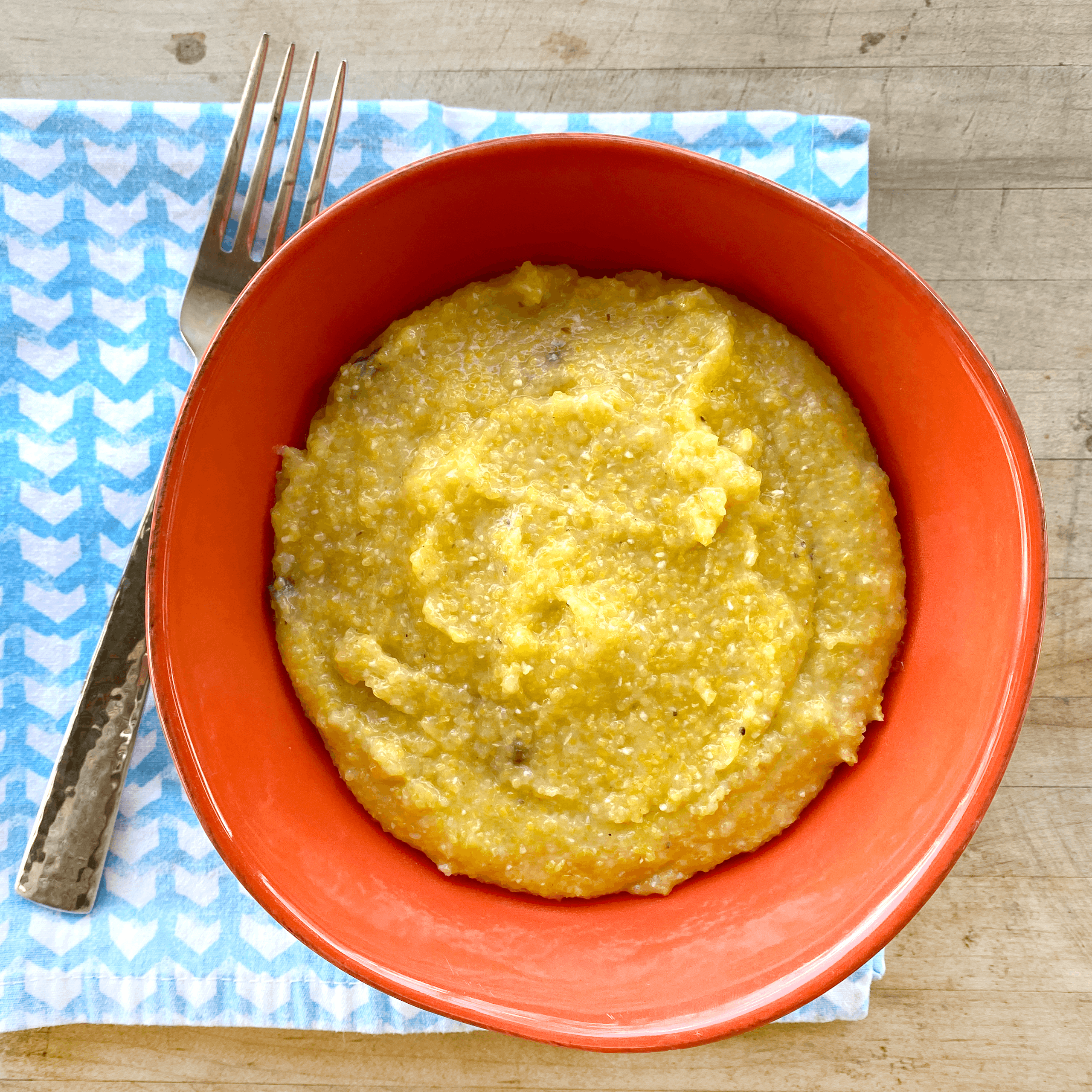 A bowl of Jalapeño, Hatch Green Chile, Cheddar Grits garnished with fresh herbs, showcasing its creamy texture and vibrant colors.