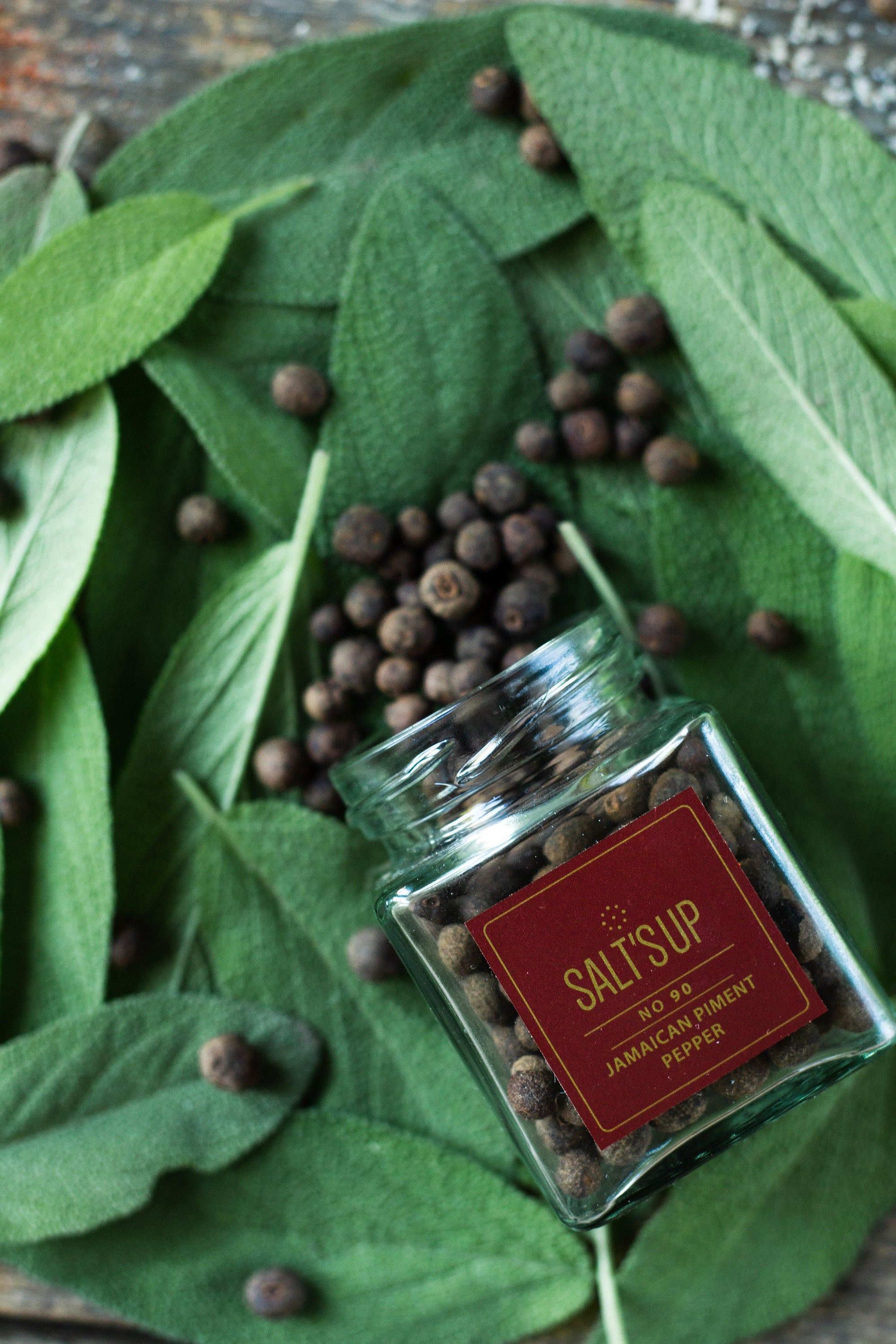 A glass jar containing 30g of Jamaican Piment pepper, showcasing its rich brown color and aromatic qualities.