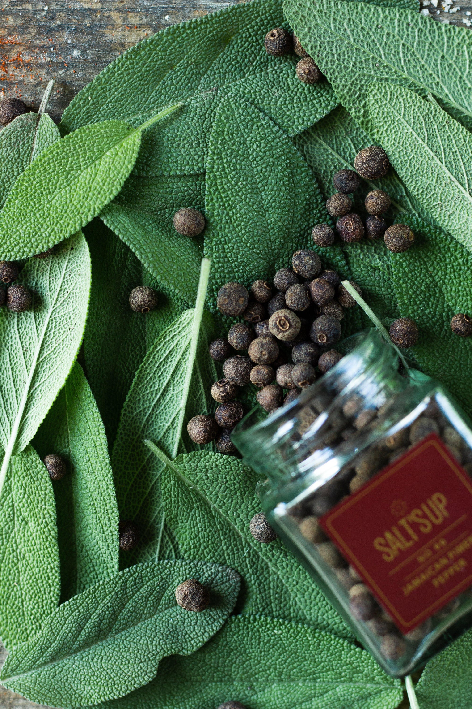 A glass jar containing 30g of Jamaican Piment pepper, showcasing its rich brown color and aromatic qualities.