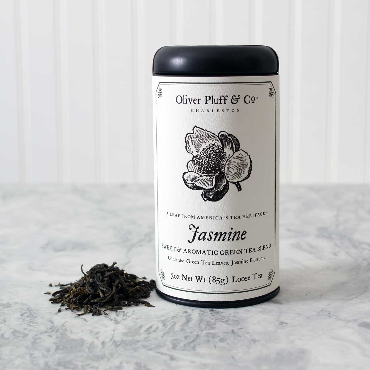 A matte black tin containing Jasmine Loose Tea, showcasing the elegant packaging and fragrant tea blend inside.