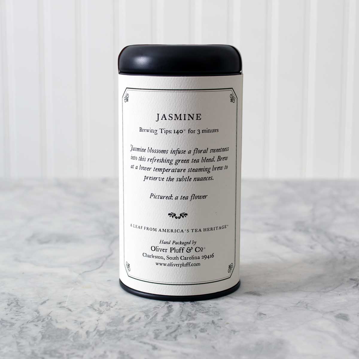 A matte black tin containing Jasmine Loose Tea, showcasing the elegant packaging and fragrant tea blend inside.