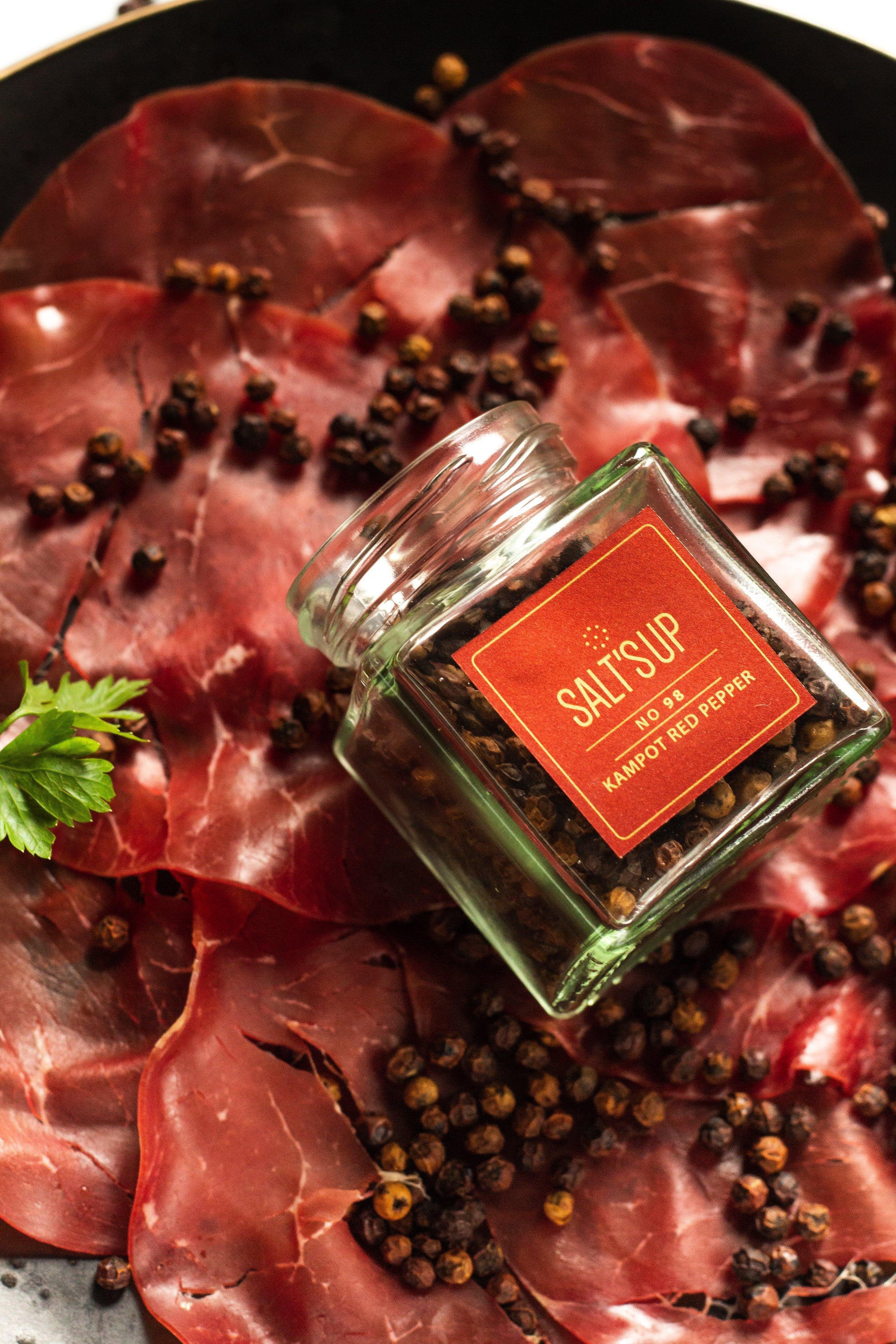 A glass jar of KAMPOT RED pepper showcasing its vibrant red color, symbolizing its unique flavor and aromatic qualities.